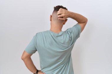 Beyaz arka planda duran sakallı İspanyol bir adam. Elleri başının üstünde şüpheyi düşünüyor. 