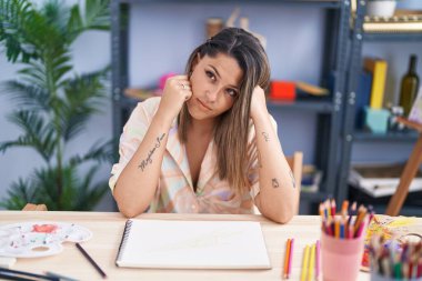 Sanat stüdyosunda defterine resim çizen genç İspanyol kadın sanatçı.