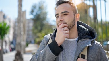 Hispanik adam şüpheli bir ifadeyle caddede duruyor