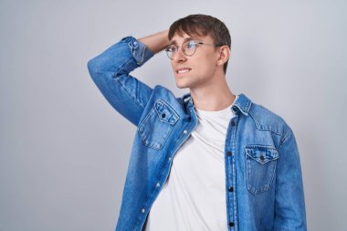 Beyaz, sarışın, gözlüklü, gülümseyen, kendine güvenen, el hareketleriyle saçlarına dokunan çekici ve şık bir adam. 