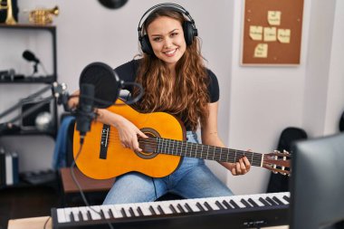 Genç, güzel, İspanyol bir müzisyen müzik stüdyosunda klasik gitar çalıyor.