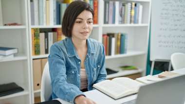 Üniversite sınıfında dizüstü bilgisayar kullanan beyaz bir kız öğrenci.