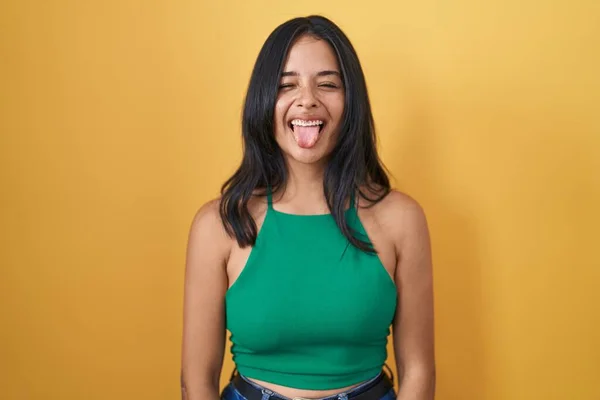 Sarı Arka Planda Dikilen Esmer Kadın Komik Bir Ifadeyle Dilini — Stok fotoğraf