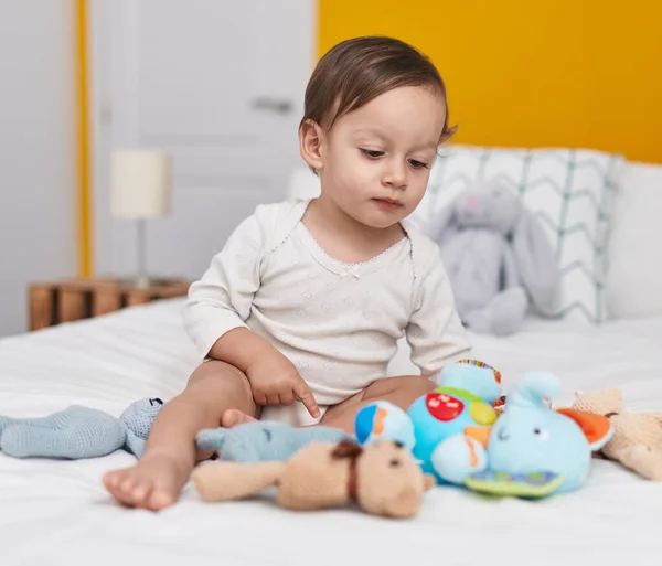 愛らしいHispanic男の子座っています上のベッドで人形とともにベッドルーム — ストック写真