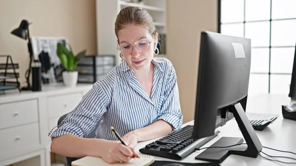若い金髪女性ビジネスワーカー コンピュータを使用して オフィスでメモを取るイヤホン — ストック写真