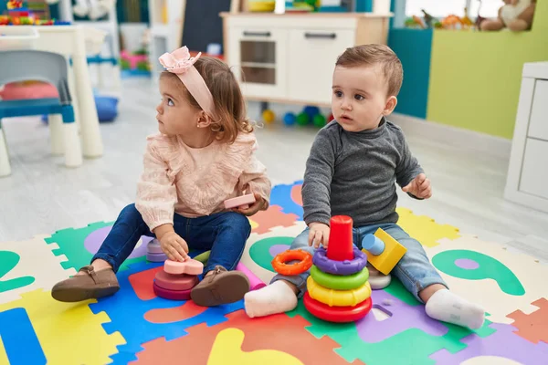 愛らしい男の子と女の子遊びますフープゲームで床に座って幼稚園 — ストック写真