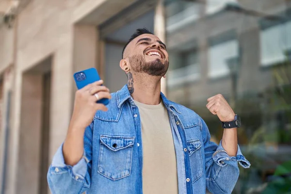 Joven Hispano Usando Smartphone Con Gesto Ganador Calle —  Fotos de Stock