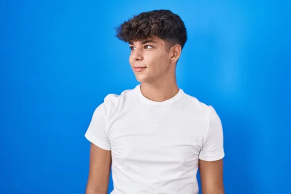 Adolescente Hispânico Sobre Fundo Azul Olhando Para Lado Com Sorriso — Fotografia de Stock