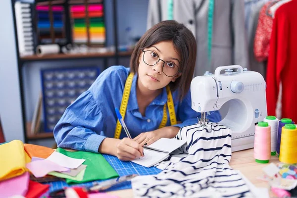 Adorable Hispanic Girl Tailor Writing Notebook Clothing Factory — Stock Photo, Image