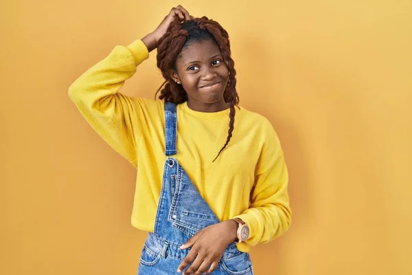 Stock image African woman standing over yellow background confuse and wondering about question. uncertain with doubt, thinking with hand on head. pensive concept. 