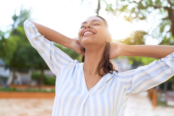 若いアフリカ系アメリカ人の女性は自信を持って笑っています公園で手でリラックス — ストック写真