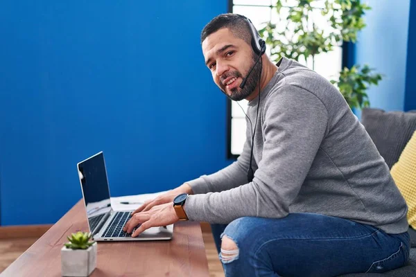 Evdeki Masada Oturan Dizüstü Bilgisayar Kulaklık Kullanan Genç Latin Adam — Stok fotoğraf