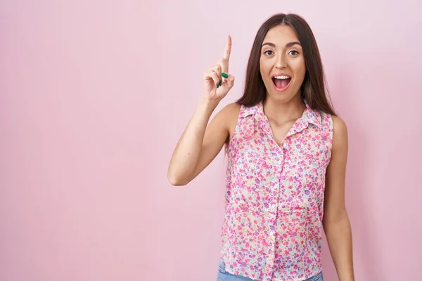 Jonge Spaanse Vrouw Met Lang Haar Roze Achtergrond Wijzend Met — Stockfoto