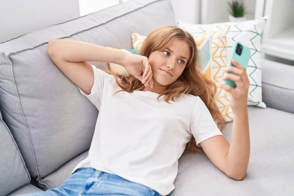 Young Blonde Girl Using Smartphone Lying Sofa Home — Fotografia de Stock