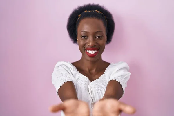 African Woman Curly Hair Standing Pink Background Smiling Hands Palms — Stock Photo, Image