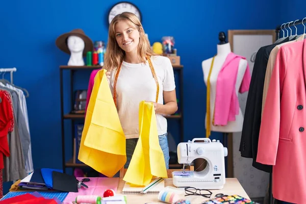 Young Blonde Girl Tailor Smiling Confident Holding Cloths Sewing Studio — Stockfoto