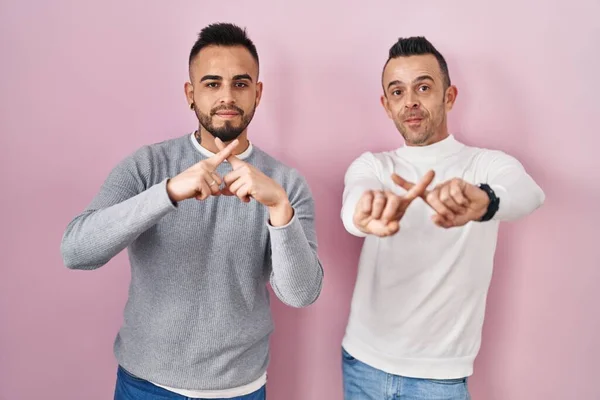Гомосексуальная Пара Стоящая Розовом Фоне Скрещивая Пальцы Делая Отрицательный Знак — стоковое фото