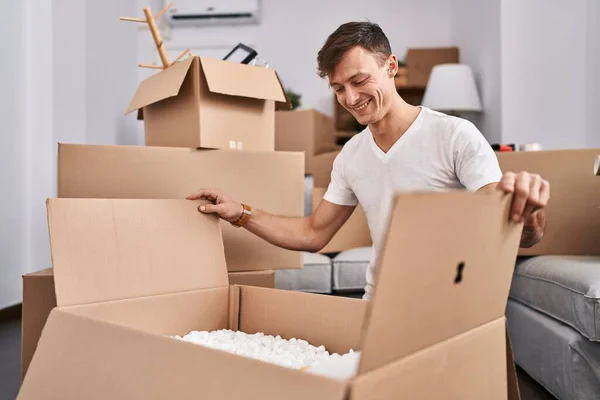 Young Man Smiling Confident Unpacking Cardboard Box New Home — Stockfoto