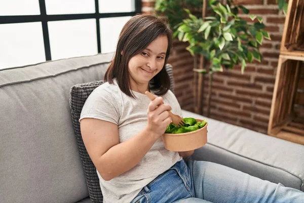 ダウン症候群女性食べるサラダ上のソファにホーム — ストック写真