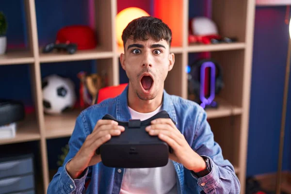 Young Hispanic Man Wearing Virtual Reality Glasses Afraid Shocked Surprise — Stock Photo, Image