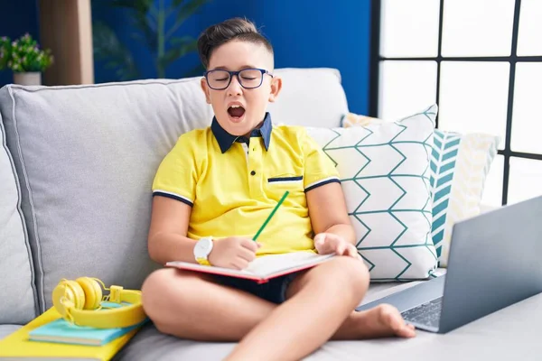 Young Hispanic Kid Doing Homework Sitting Sofa Angry Mad Screaming — Stockfoto