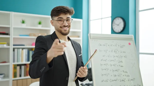 Young arab man teacher teaching maths lesson pointing with finger to camera at university classroom
