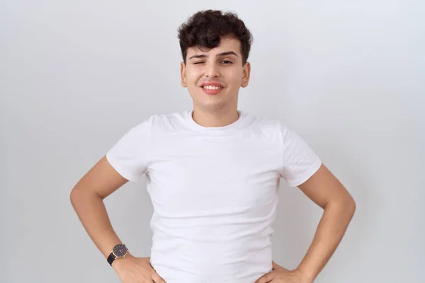 年轻的非二元男人 身穿休闲的白色T恤 眨着眼睛 带着性感的表情 开朗而快乐地看着摄像机 — 图库照片
