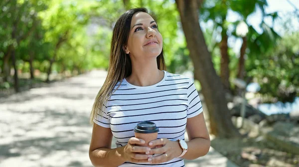 Orta Doğulu bir kadın gülümsüyor. Parka bakıyor.