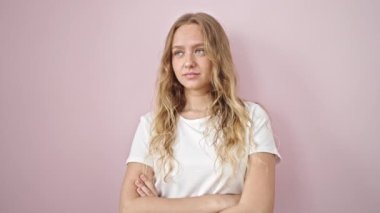 Young blonde woman standing with surprise expression over isolated pink background