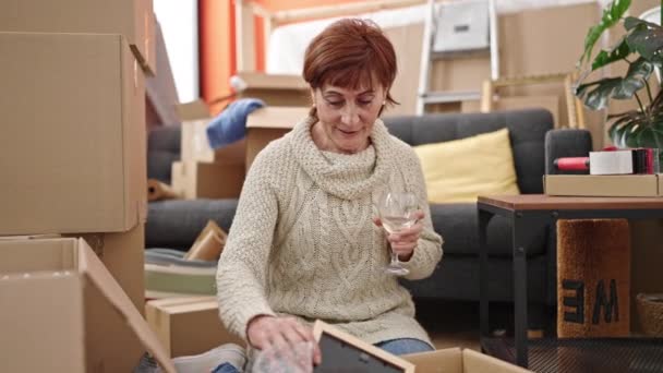 Mujer Hispana Madura Desempacando Caja Cartón Bebiendo Vino Mirando Marco — Vídeo de stock