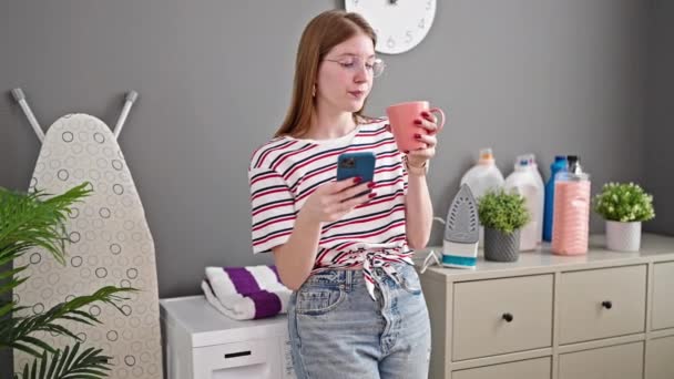 Mujer Rubia Joven Usando Smartphone Bebiendo Café Esperando Lavadora Sala — Vídeos de Stock