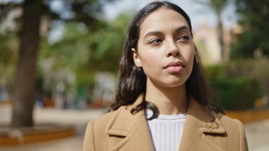 Parkta ciddi bir ifadeyle duran genç, güzel İspanyol kadın.