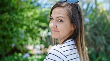 Ortadoğulu kadın parkta kendinden emin gülümsüyor.