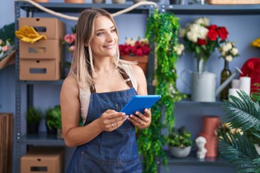 Young caucasian woman florist smiling confident using touchpad at florist
