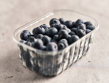  Plastik kutu mermer yüzeyinde lezzetli bir yaban mersini grubu.