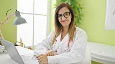 Orta Doğulu kadın doktor klinikte çalışırken dizüstü bilgisayar kullanıyor.