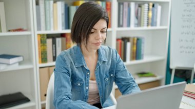 Üniversite sınıfında dizüstü bilgisayar kullanan beyaz bir kız öğrenci.