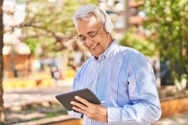 Kıdemli adam parktaki dokunmatik ekranda video izlerken kendinden emin gülümsüyor.