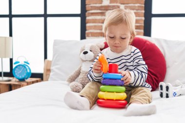 Sevimli beyaz çocuk yatak odasında yatağında basketbol oynuyor.