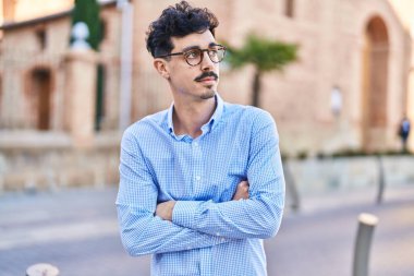 Young caucasian man standing with arms crossed gesture and relaxed expression at street