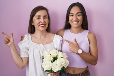 İspanyol anne ve kızı ellerinde neşe dolu bir buket çiçek tutarken yüzünde bir gülümseme, mutlu ve doğal bir ifadeyle elleri ve parmaklarıyla yüzünü gösteriyordu. 