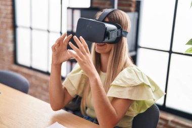 Young beautiful hispanic woman business worker using virtual reality glasses at office