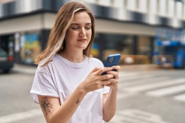 Sokakta akıllı telefon kullanan kendine güvenen genç bir kadın.