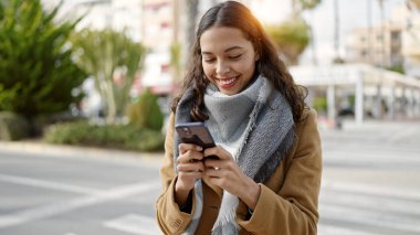 Sokakta gülümseyen akıllı telefon kullanan genç, güzel İspanyol kadın.