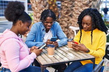Afro-Amerikalı arkadaşlar akıllı telefon kullanıyor kahve içiyor kahve dükkanının terasında bankta oturuyor.