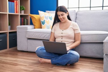 Evde dizüstü bilgisayar kullanan genç, güzel İspanyol kadın.