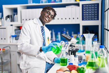 Afrikalı Amerikalı bilim adamı laboratuarda test tüpüne sıvı döküyor.