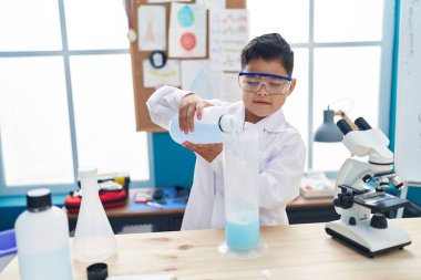 Sevimli İspanyol öğrenci laboratuvar sınıfında kendine güvenen bir öğrenci test tüpüne sıvı döküyor.