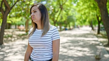 Orta Doğulu kadın üzgün bir ifadeyle parkta dikiliyor.