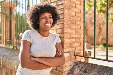 Sokakta kollarını kavuşturmuş Afro-Amerikalı bir kadın.